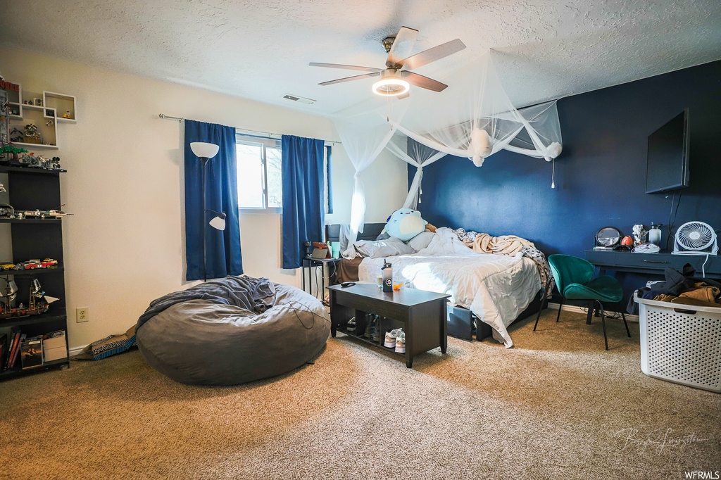 Bedroom with ceiling fan, a textured ceiling, and carpet