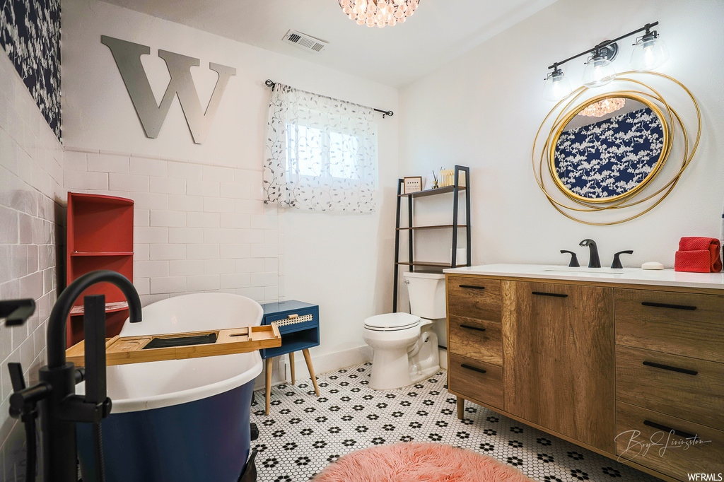 Bathroom with toilet, tile walls, tile floors, a washtub, and vanity