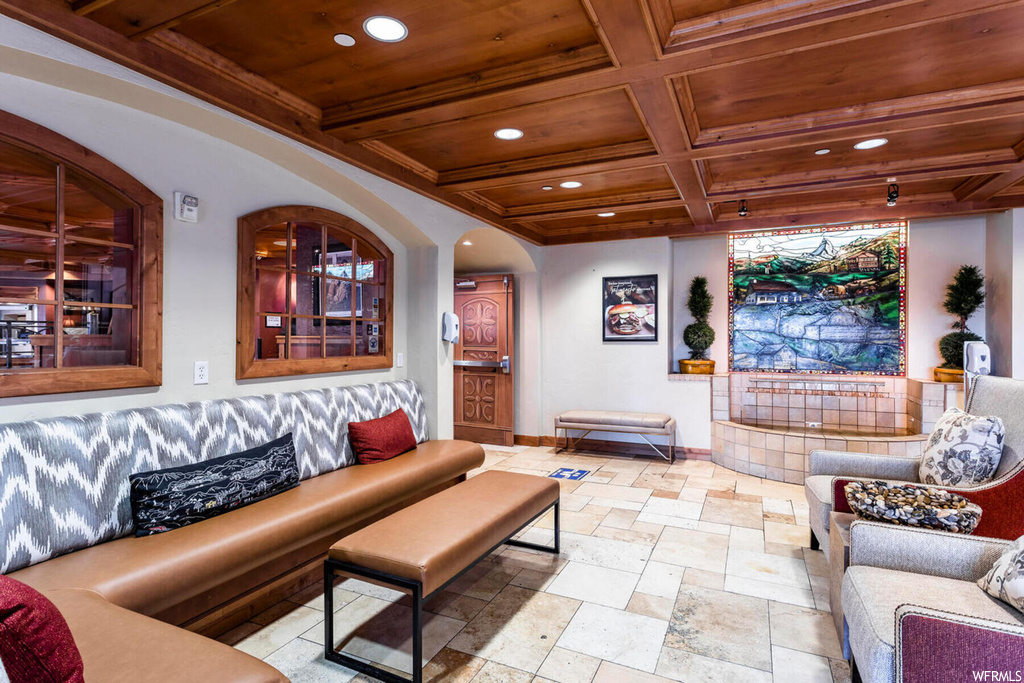 Living room featuring wood ceiling, beam ceiling, coffered ceiling, and light tile floors