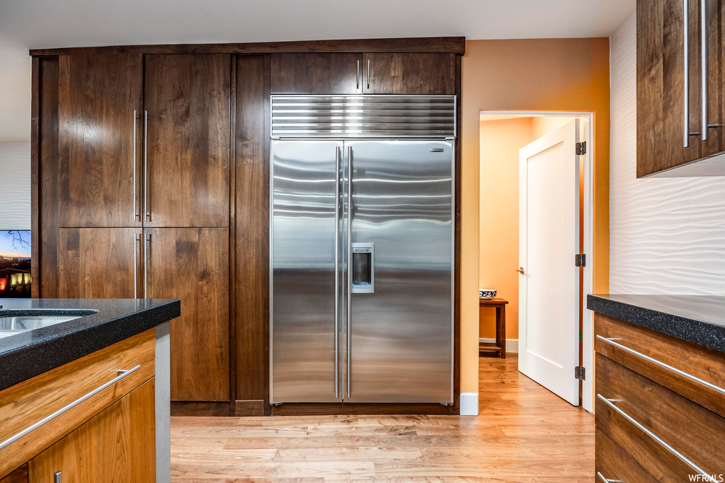 Kitchen featuring light wood-type flooring and stainless steel built in fridge