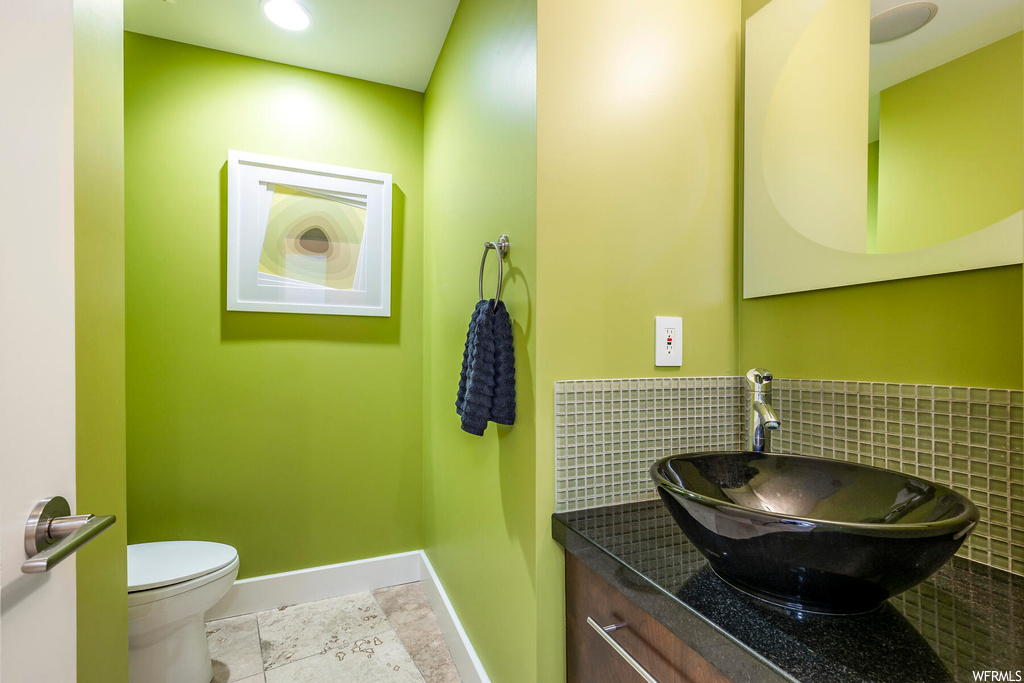 Bathroom featuring toilet, tile floors, large vanity, and backsplash