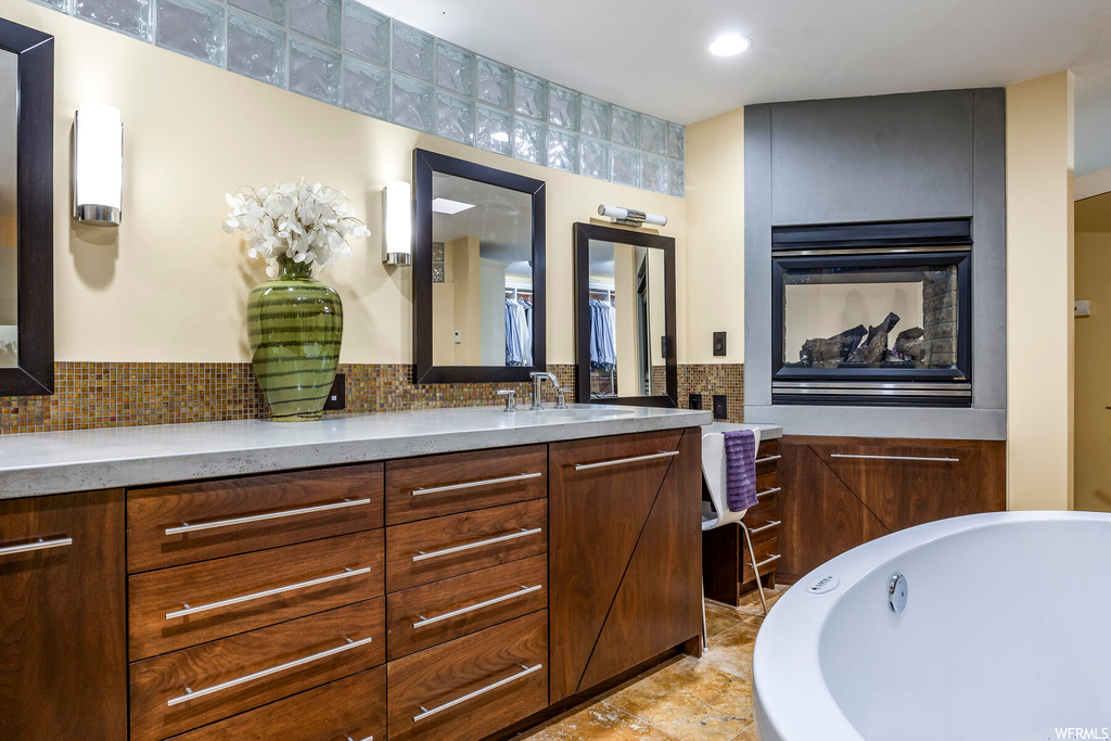 Bathroom featuring a tub, vanity, tile floors, and tasteful backsplash