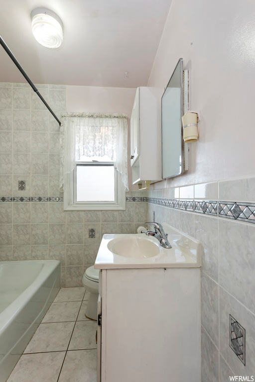 Full bathroom featuring tile floors, tile walls, large vanity, and tiled shower / bath