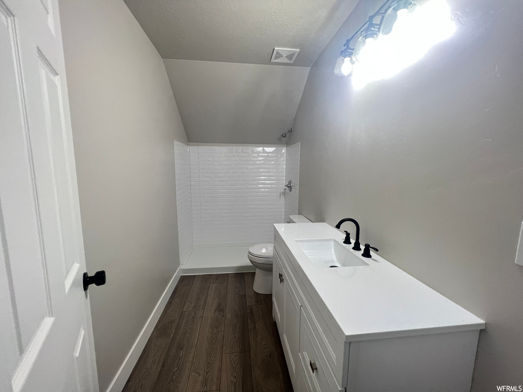 Bathroom with toilet, a textured ceiling, a shower, hardwood / wood-style flooring, and vanity