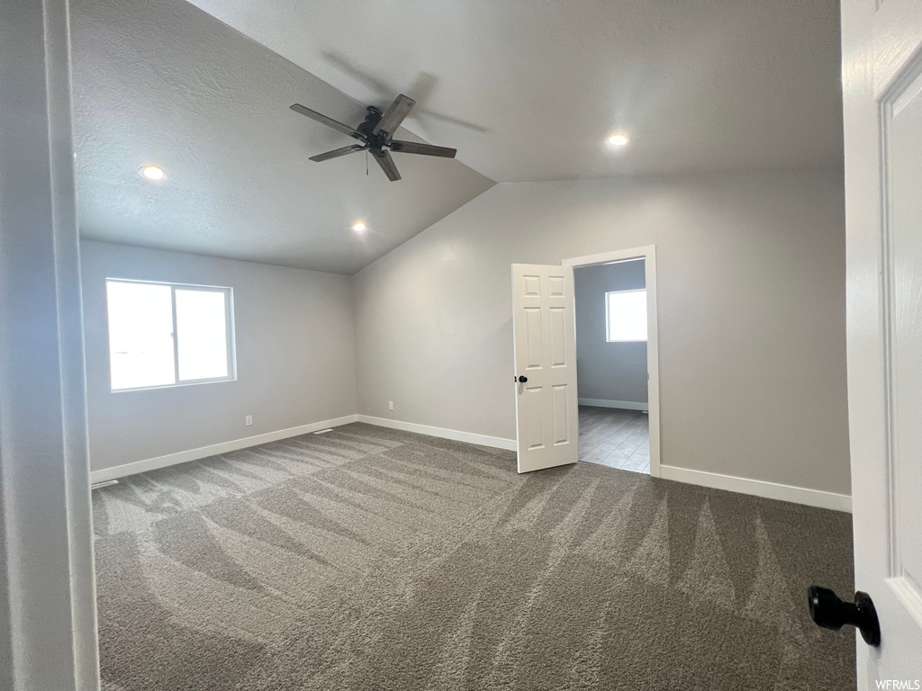 Spare room with ceiling fan, vaulted ceiling, and carpet floors