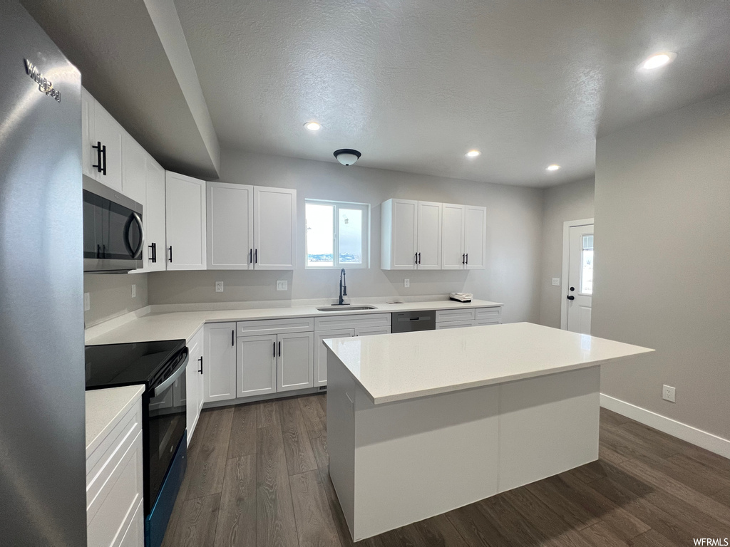 Kitchen with sink, a center island, dark hardwood / wood-style flooring, black appliances, and white cabinetry