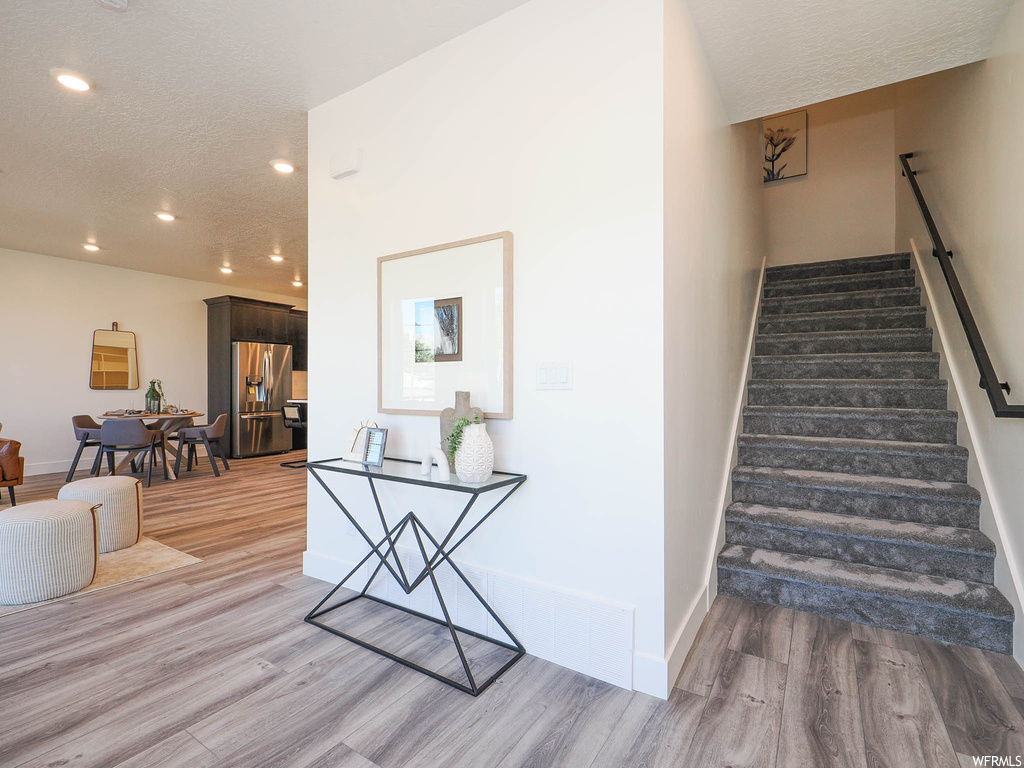 Stairway featuring light hardwood / wood-style flooring and a textured ceiling