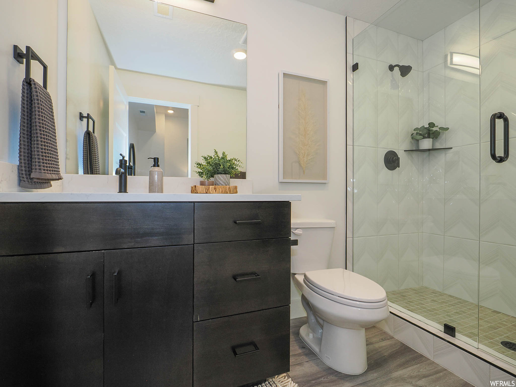Bathroom featuring vanity, toilet, a shower with shower door, and hardwood / wood-style flooring