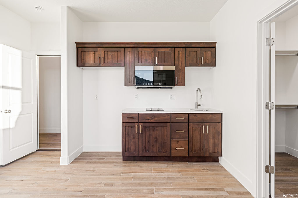 Kitchen with sink, light hardwood / wood-style flooring, and dark brown cabinetry