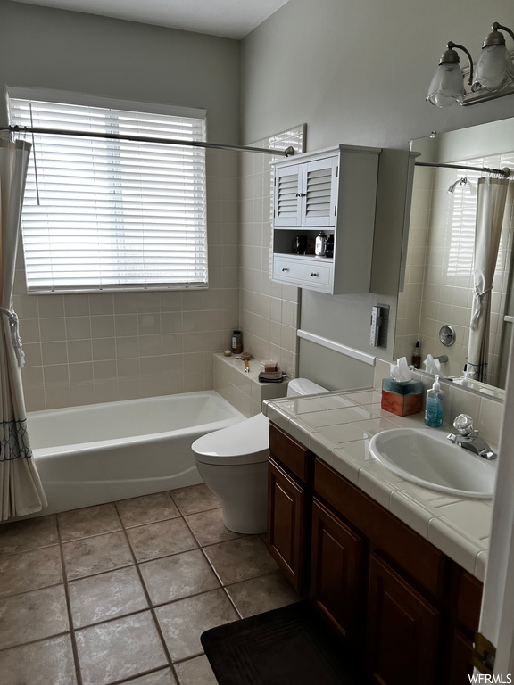 Bathroom with toilet, plenty of natural light, oversized vanity, and tile floors