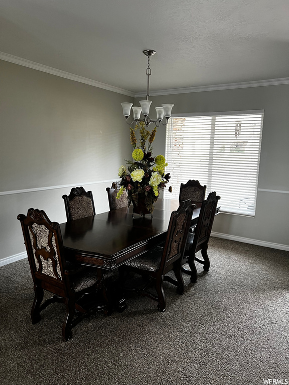 Dining space with dark carpet, an inviting chandelier, and crown molding