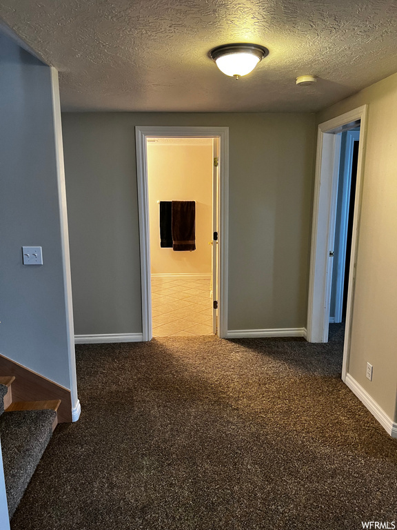 Spare room with dark carpet and a textured ceiling