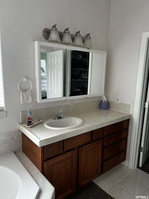 Bathroom with tile floors, vanity with extensive cabinet space, and a bathing tub