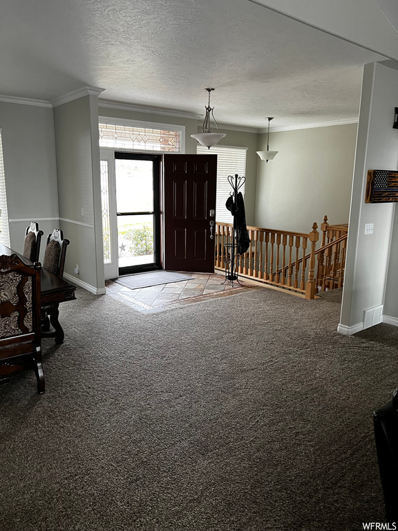 Carpeted foyer with a textured ceiling and crown molding