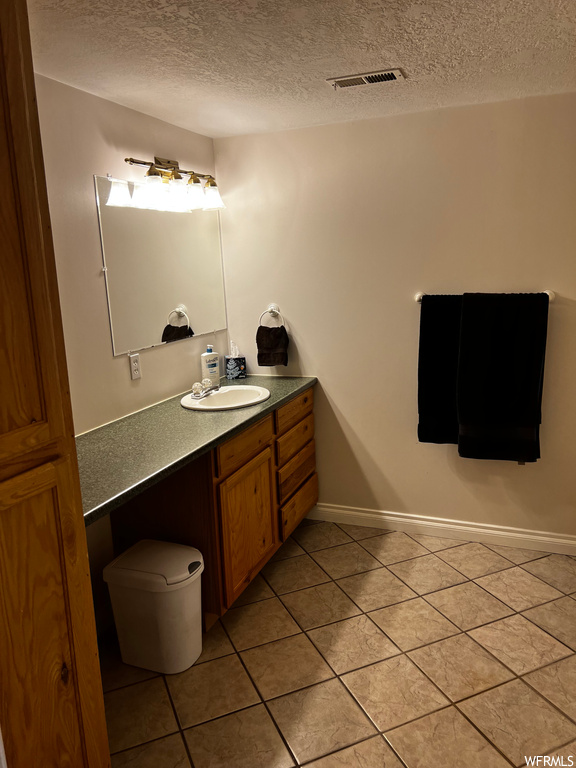 Bathroom with tile flooring, a textured ceiling, and vanity