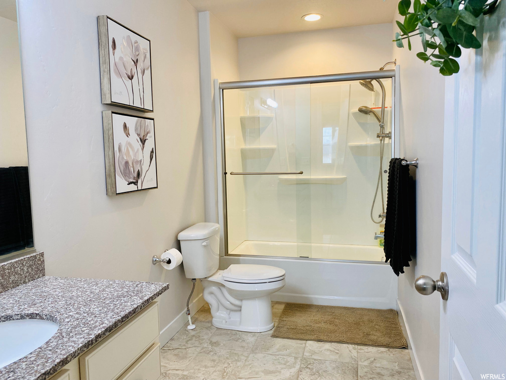 Full bathroom featuring bath / shower combo with glass door, toilet, tile flooring, and vanity