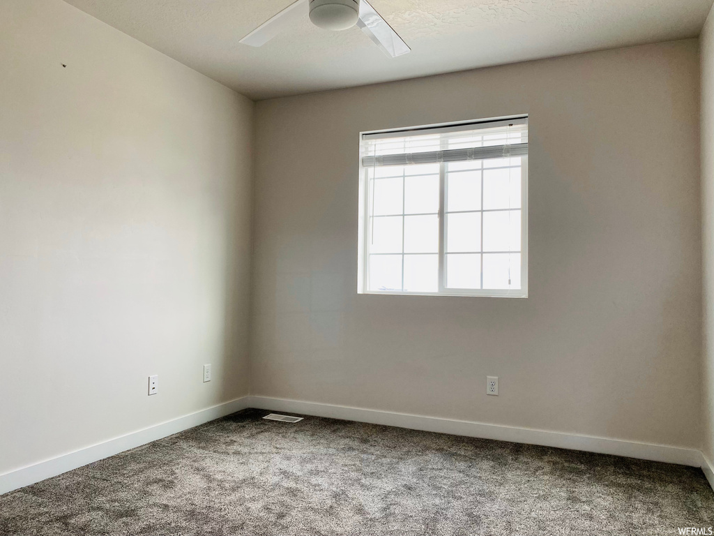 Unfurnished room featuring ceiling fan and carpet