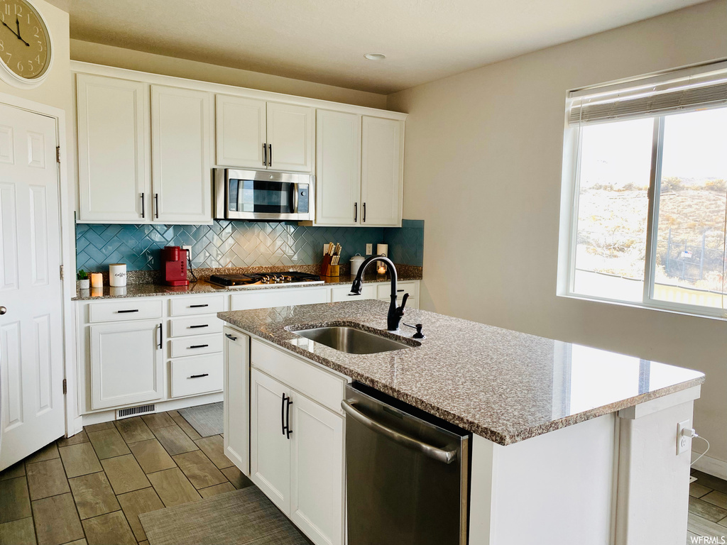 Kitchen with white cabinets, sink, tasteful backsplash, and stainless steel appliances