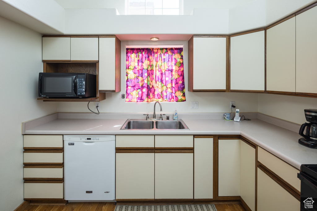 Kitchen featuring white cabinets, sink, white dishwasher, and dark wood-type flooring