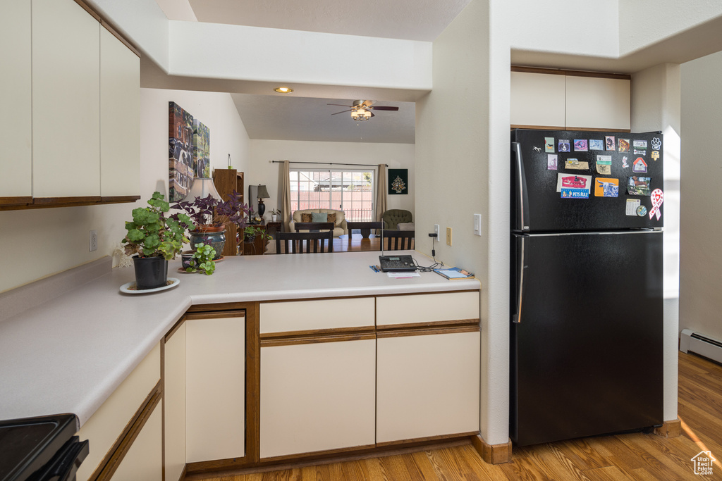 Kitchen featuring white cabinetry, black refrigerator, and light wood-type flooring