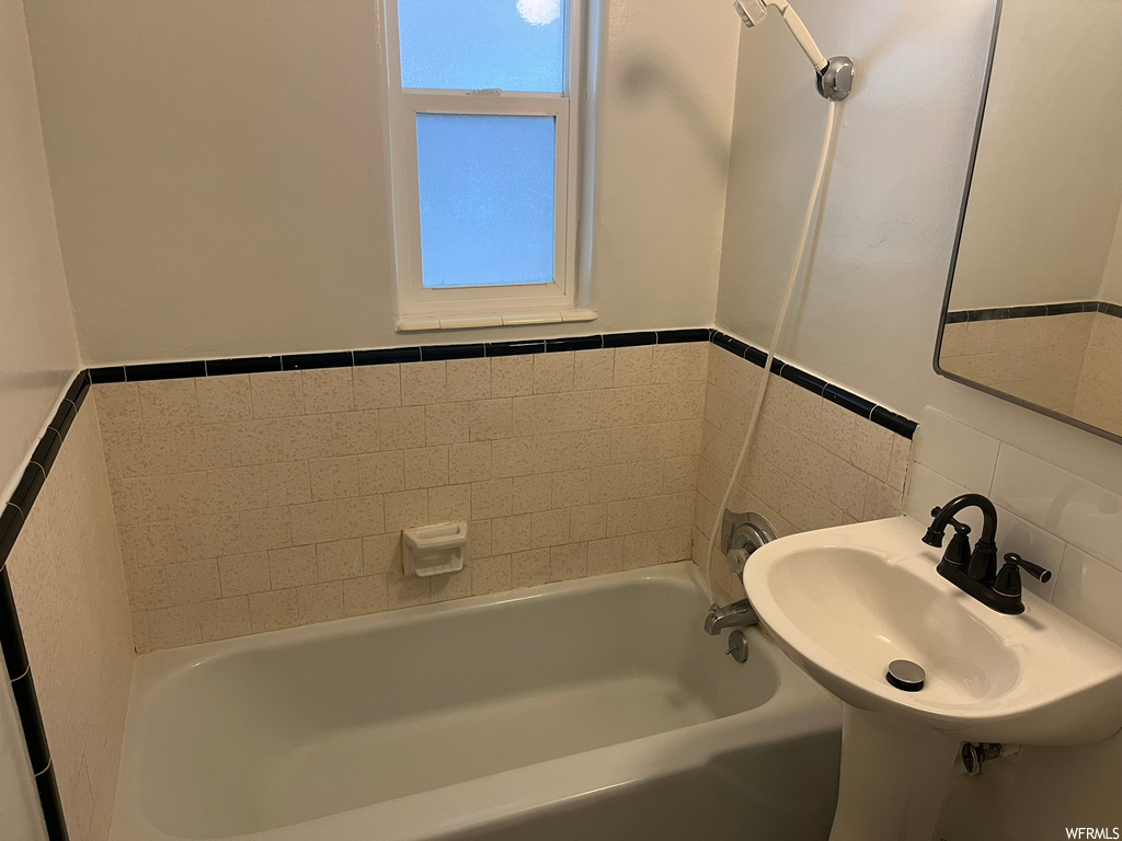 Bathroom featuring sink, tile walls, and tub / shower combination