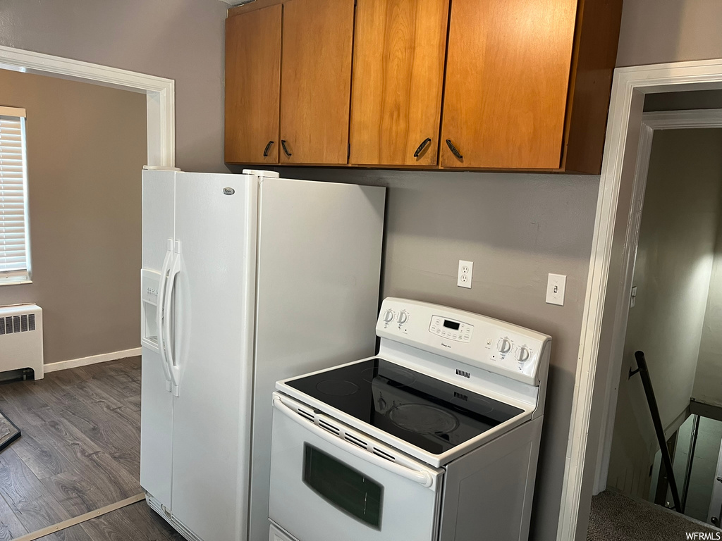 Kitchen featuring dark hardwood / wood-style floors, white appliances, and radiator