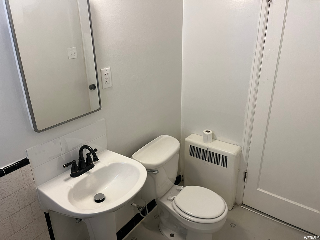 Bathroom with toilet, sink, and radiator heating unit