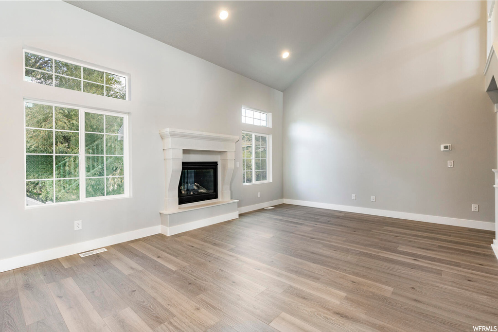 Unfurnished living room featuring high vaulted ceiling and light hardwood / wood-style flooring