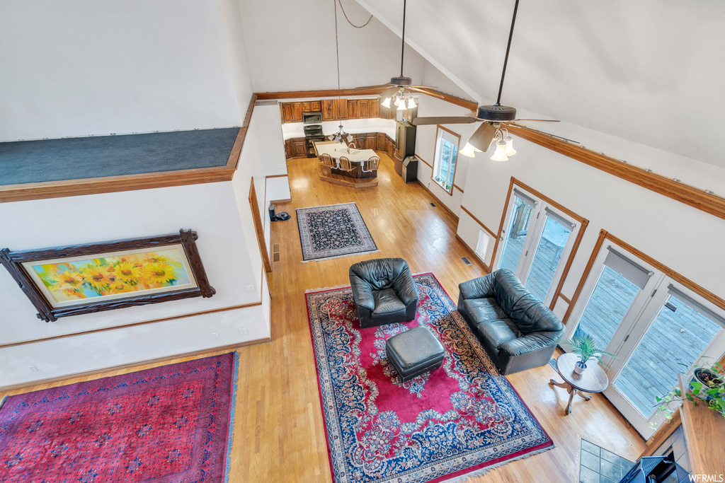 Living room featuring light wood-type flooring, high vaulted ceiling, and ceiling fan