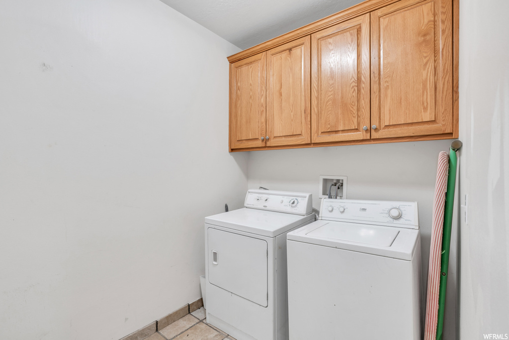 Laundry area featuring cabinets, washer and dryer, hookup for a washing machine, and light tile floors