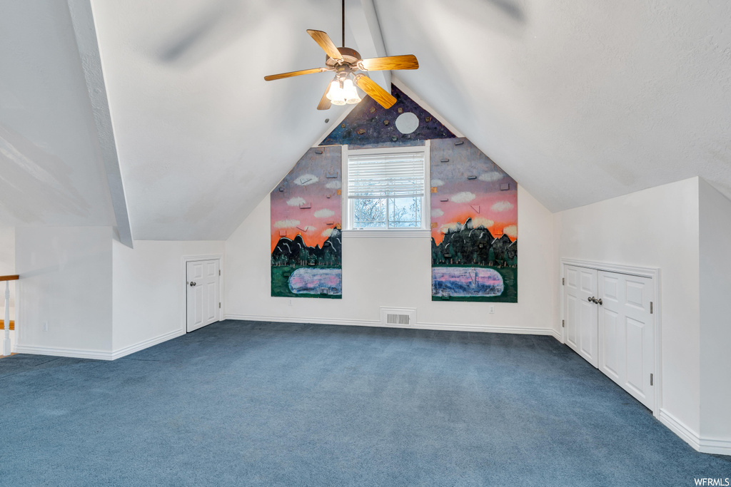 Bonus room featuring vaulted ceiling, dark colored carpet, and ceiling fan
