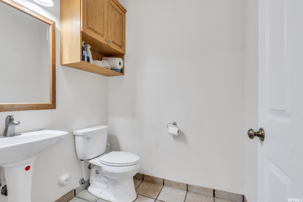 Bathroom featuring sink, tile floors, and toilet