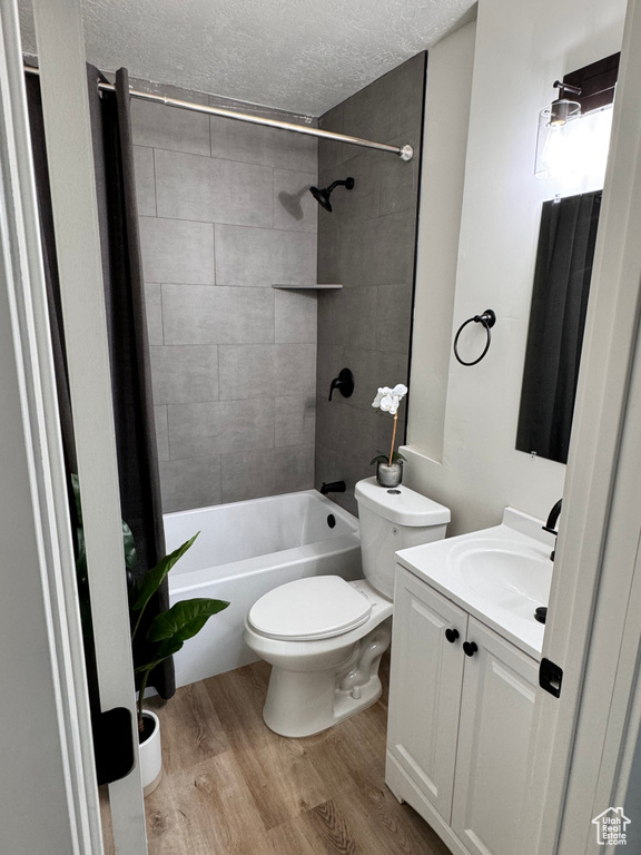 Full bathroom featuring vanity, tiled shower / bath, a textured ceiling, wood-type flooring, and toilet