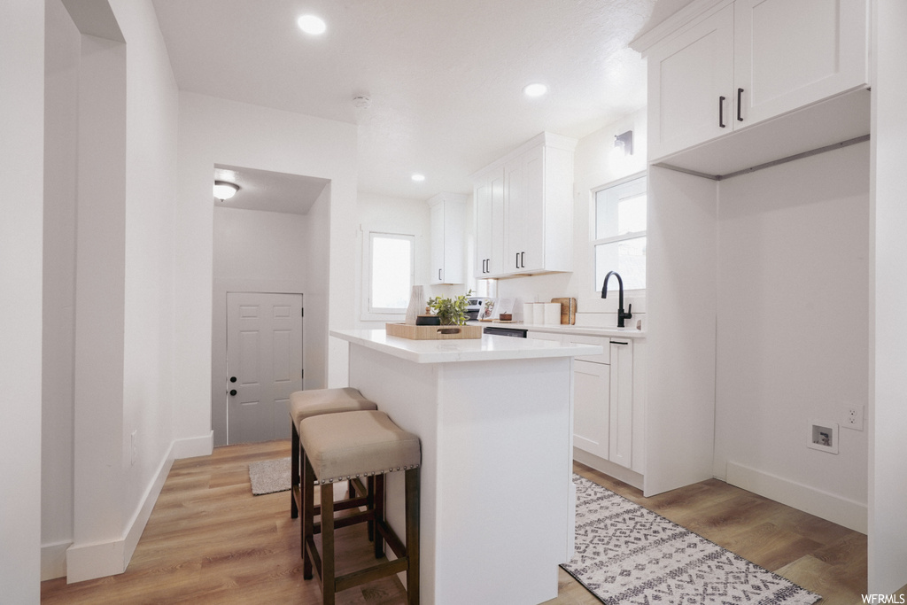 Kitchen featuring white cabinetry, light wood-type flooring, and a kitchen bar