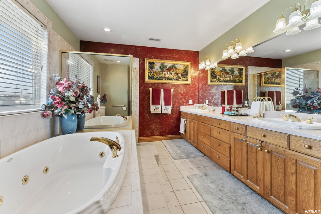 Bathroom with tiled bath, double sink vanity, and tile flooring