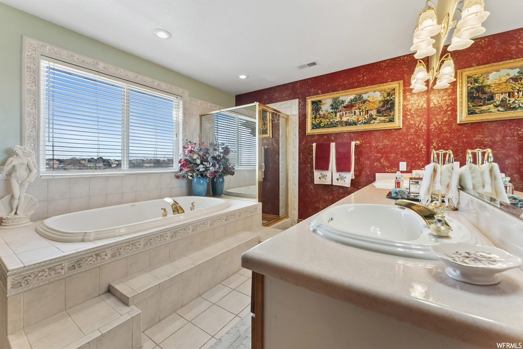 Bathroom with an inviting chandelier, independent shower and bath, vanity, and tile flooring