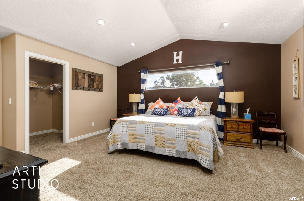 Bedroom with lofted ceiling, a closet, light colored carpet, and a spacious closet