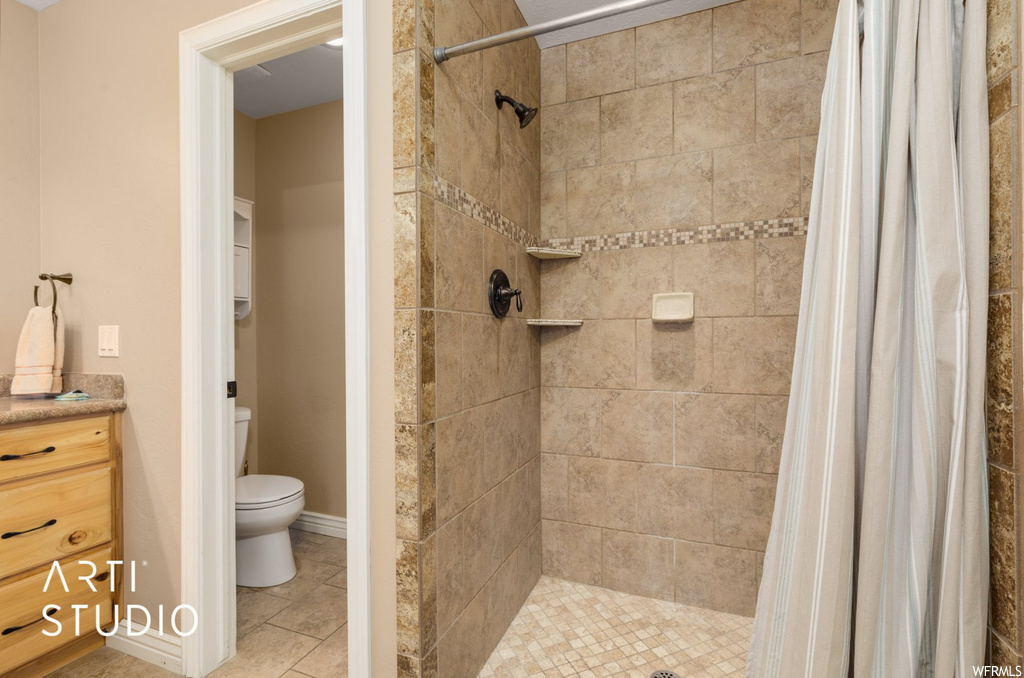 Bathroom featuring tile floors, vanity, toilet, and a shower with shower curtain