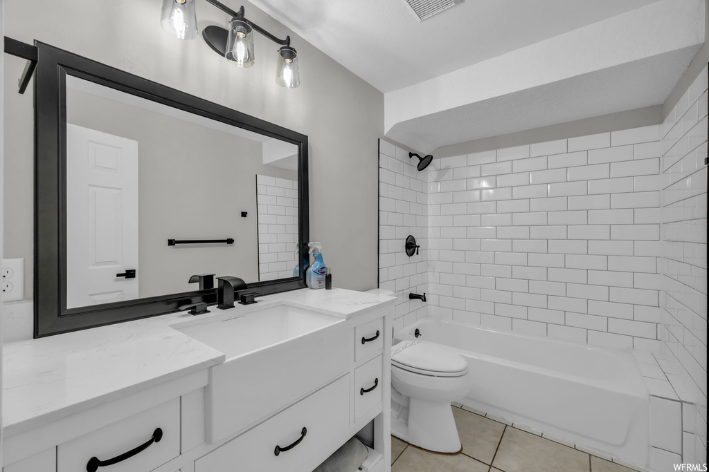Full bathroom featuring tiled shower / bath, toilet, tile flooring, and oversized vanity