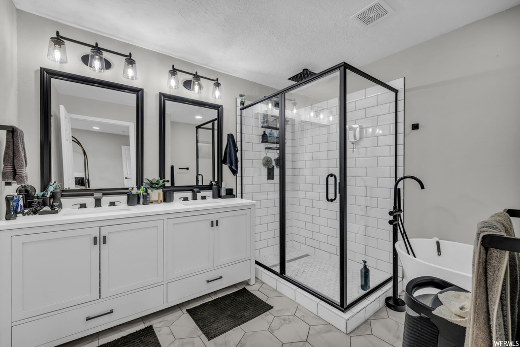 Bathroom featuring double sink vanity, an enclosed shower, and tile flooring