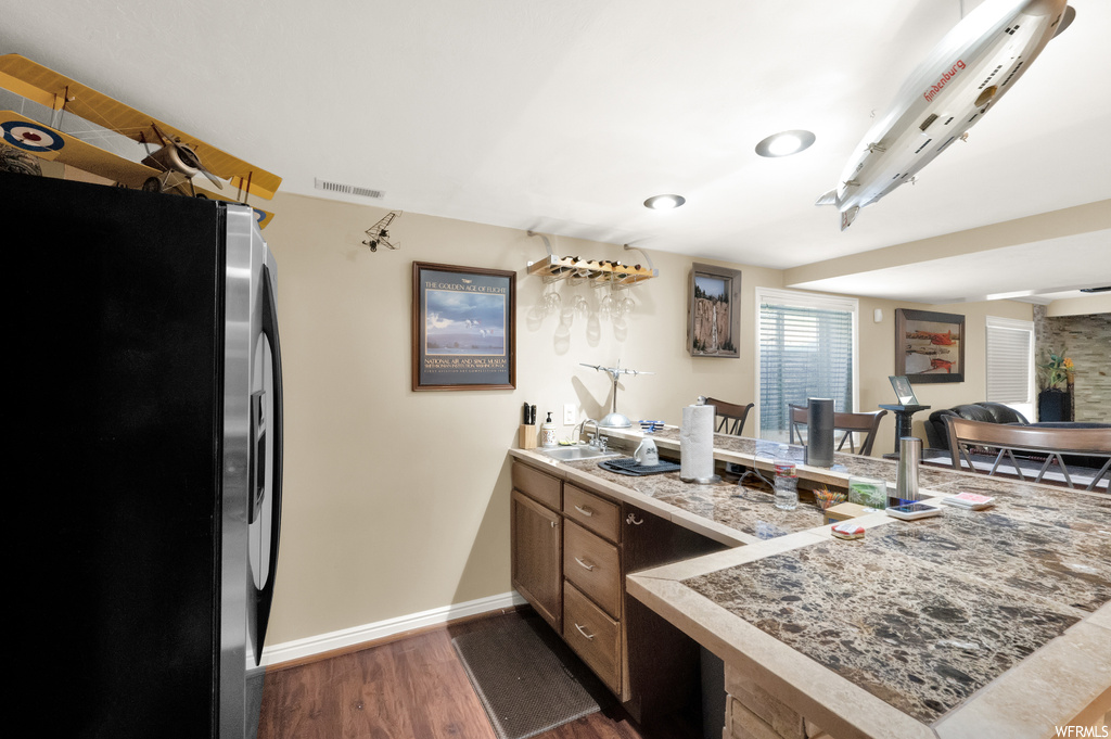Kitchen with sink, kitchen peninsula, stainless steel refrigerator, and dark hardwood / wood-style floors