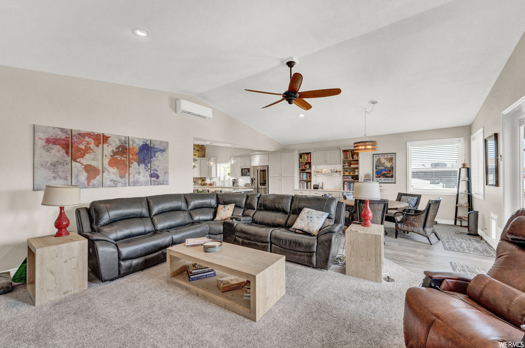 Carpeted living room featuring vaulted ceiling, a wall unit AC, and ceiling fan