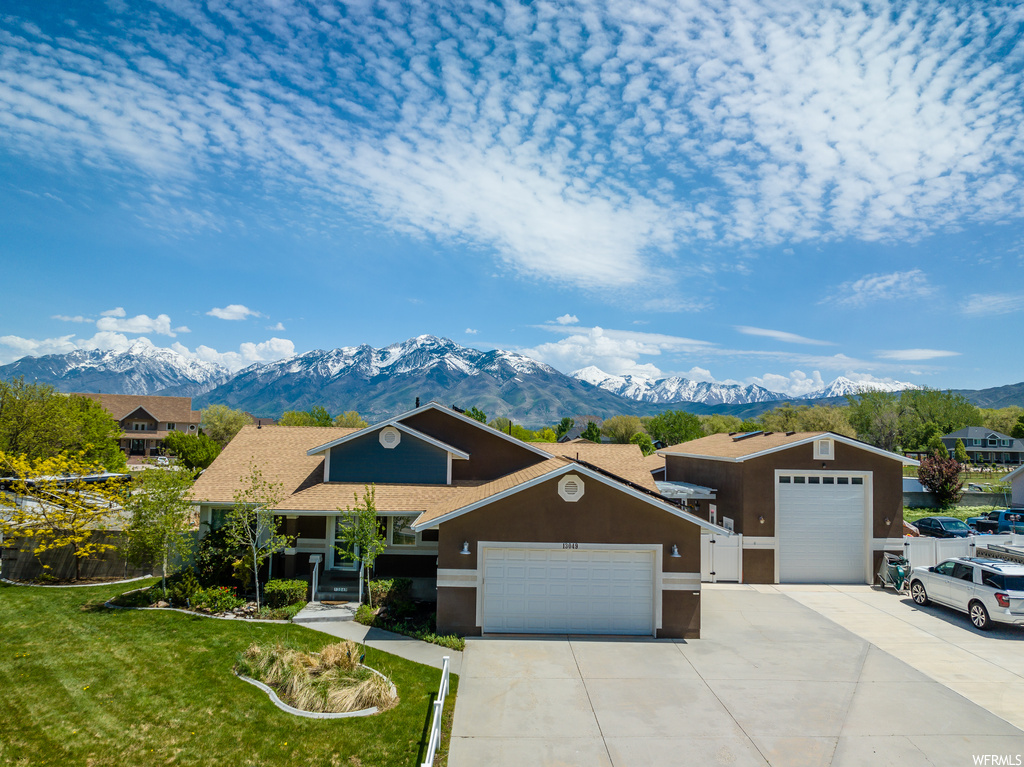 Ranch-style house with a garage, a front lawn, and a mountain view
