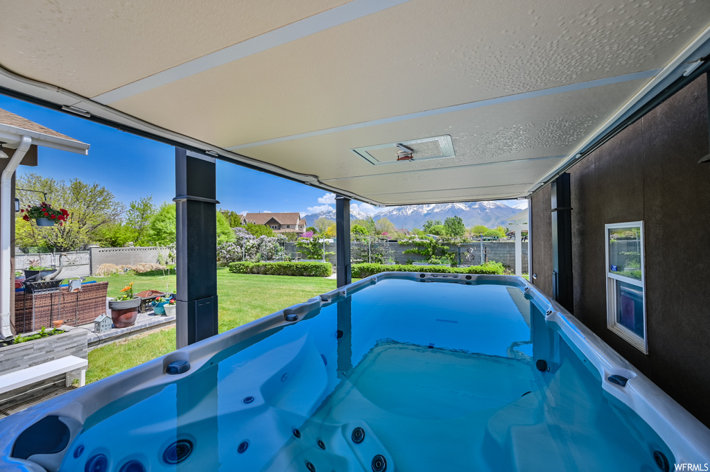 View of pool with a hot tub and a yard