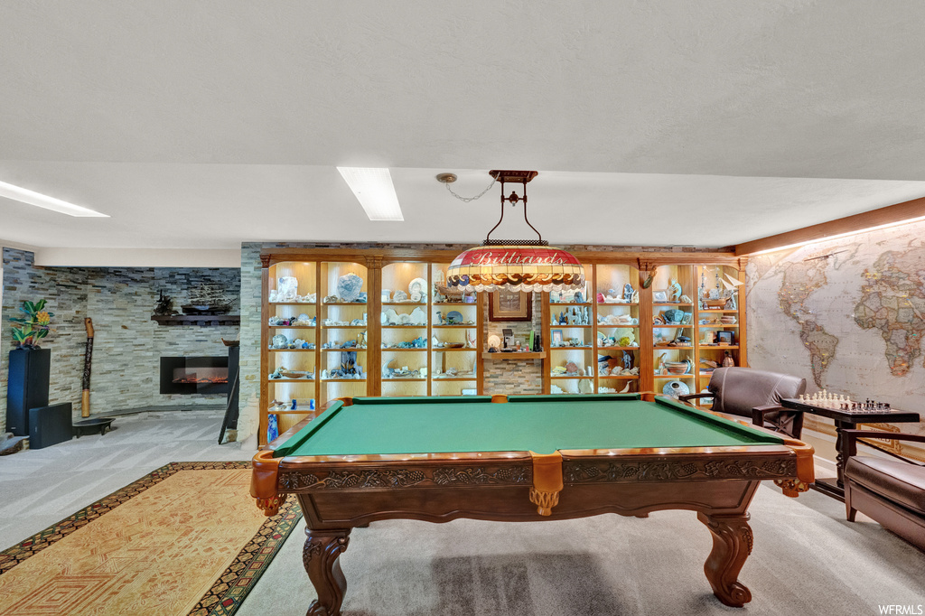 Recreation room featuring pool table, light colored carpet, and a fireplace