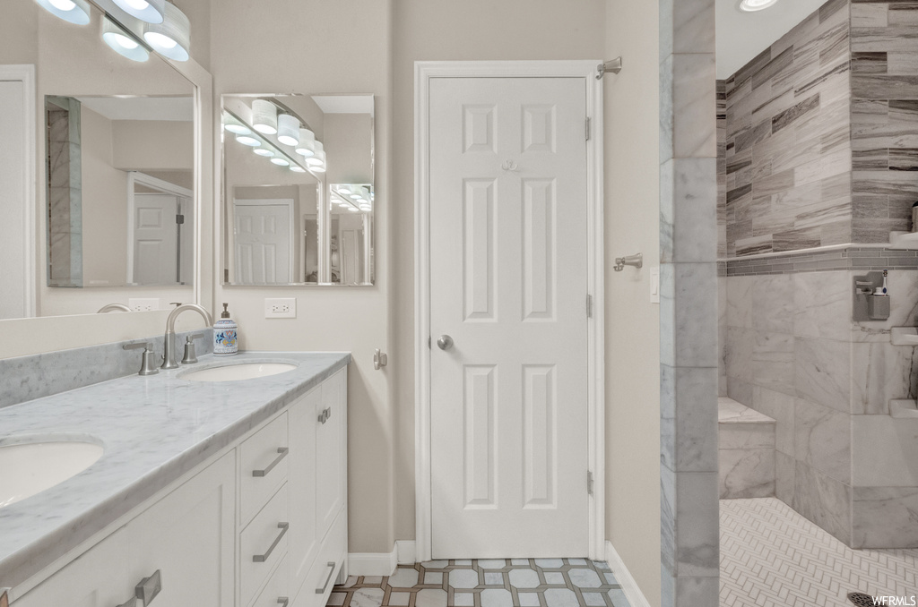 Bathroom featuring dual vanity, tile flooring, and tiled shower