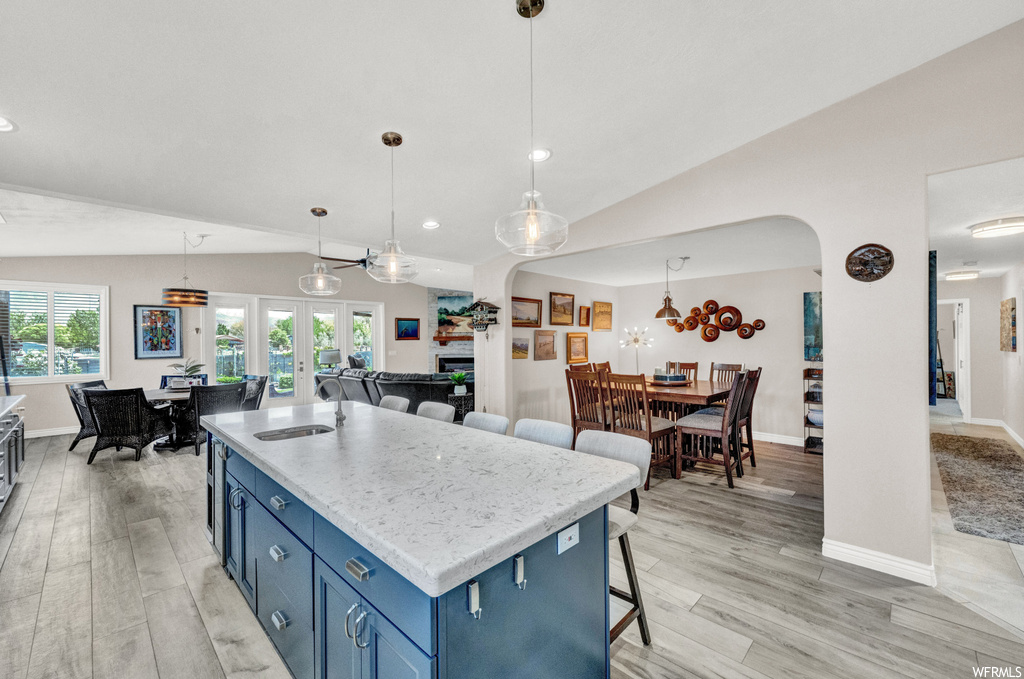 Kitchen with vaulted ceiling, light hardwood / wood-style flooring, pendant lighting, and a breakfast bar