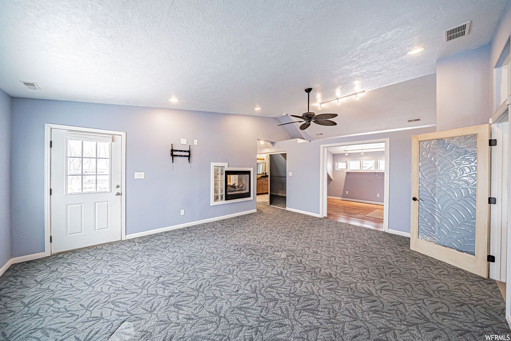 Interior space featuring plenty of natural light, dark carpet, a fireplace, and ceiling fan