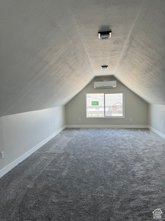 Bonus room with lofted ceiling, carpet flooring, and a textured ceiling