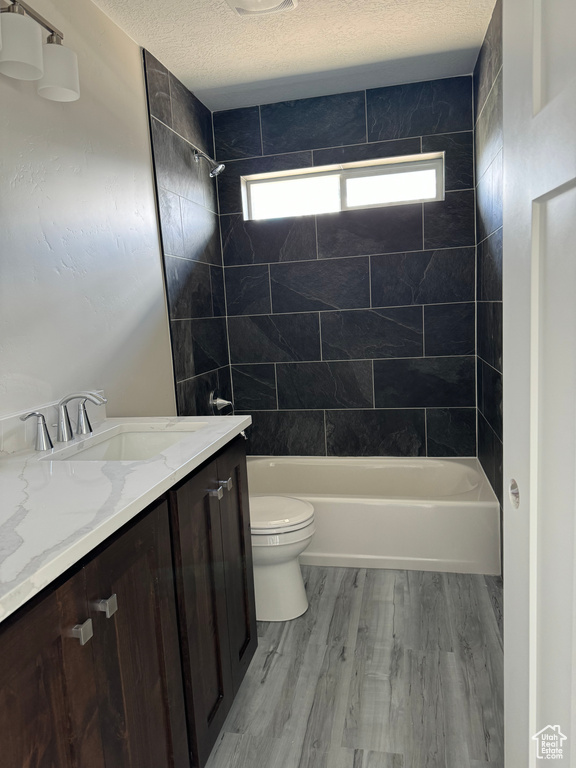 Full bathroom featuring a textured ceiling, toilet, vanity, and hardwood / wood-style floors